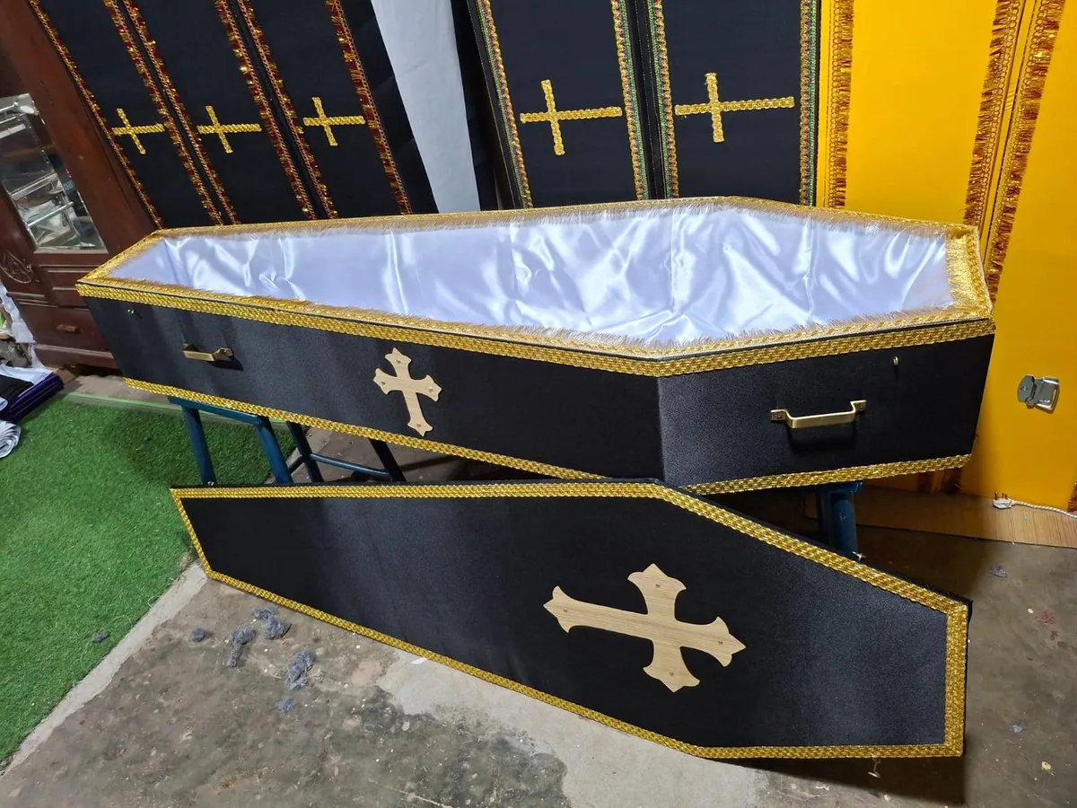 Black coffin with white satin lining and gold cross