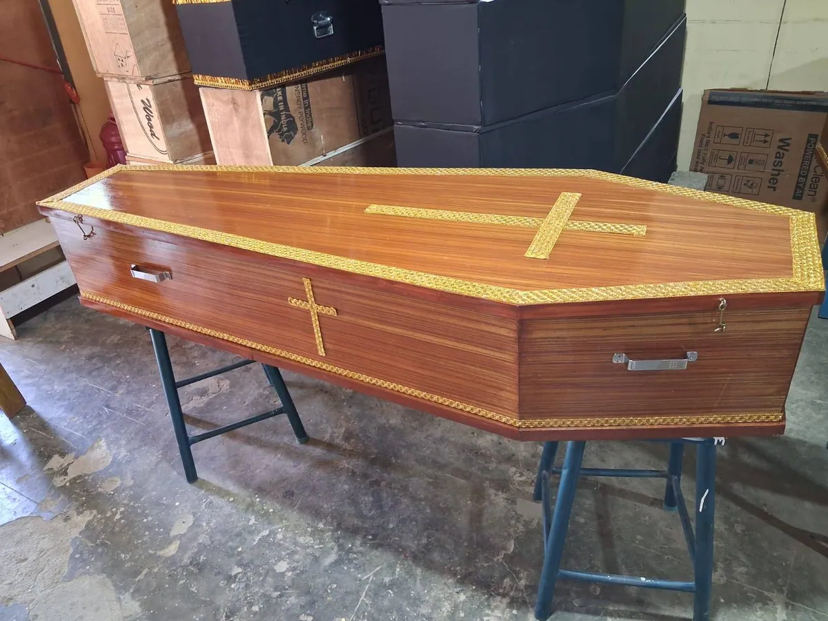 Polished wooden coffin with gold cross